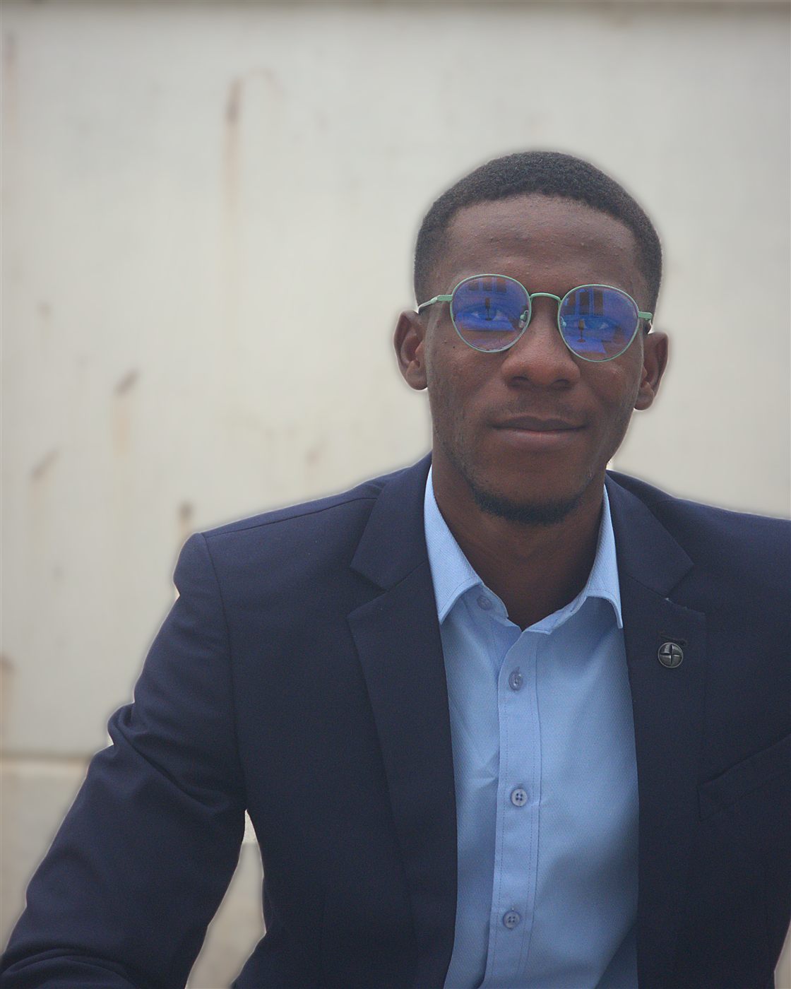 Seated portrait of Tolulope Ajidahun in a navy suit and light blue shirt